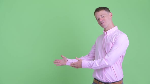 Portrait of Happy Businessman Showing Something and Giving Thumbs Up