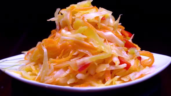 salad of fresh vegetables on a white plate rotates on black background.