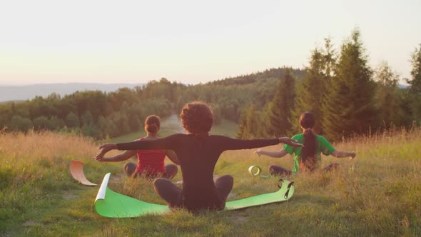 Rear View of Peaceful Sporty Fitness Multiracial Females Meditating Doing Sun Salutation Yoga Pose