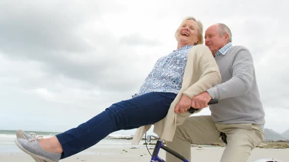 Side view of old caucasian senior couple sitting on a bicycle at beach 4k