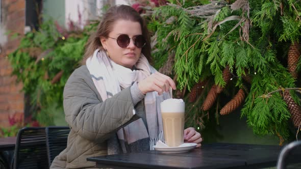 Tourist Woman in Sunglasses Drinks Hot Coffee in the Street Cafe of Old Town in Autumn