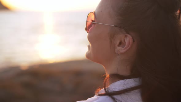 Shooting Over Shoulder of Cheerful Young Smiling Woman Dancing in Slow Motion in Sunbeam Outdoors