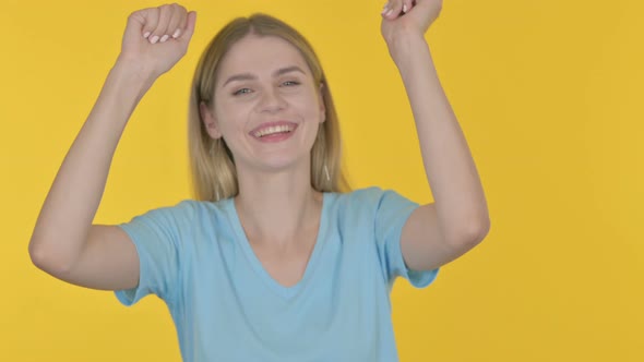 Young Woman Dancing in Joy on Yellow Background