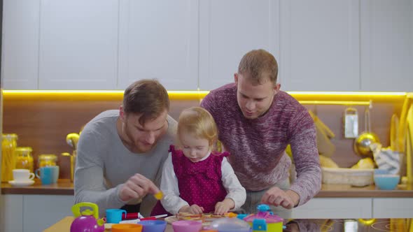 Caring Gay Parents with Kid Playing Game Indoors