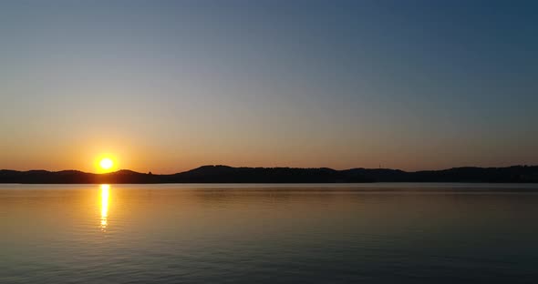 Relaxing sunset time lapse over a calm lake with mountains in the background