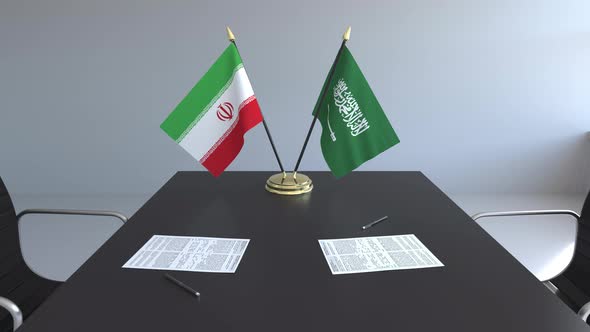 Flags of Iran and Saudi Arabia and Papers on the Table