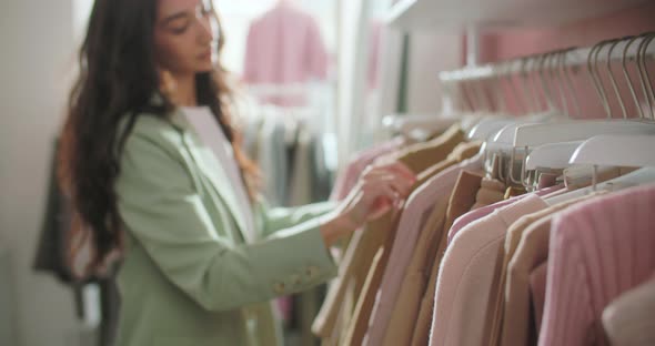 Closeup of Female Hands Plucked Hanger Choosing Clothes in a Clothing Store