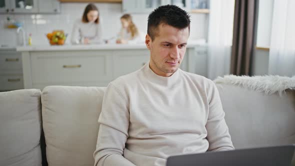 Close Up Portrait of Man Working on Laptop at Home His Wife and Daughter Studying on Background Slow