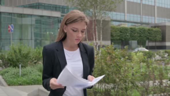 Businesswoman Reading Document While Walking on the Street