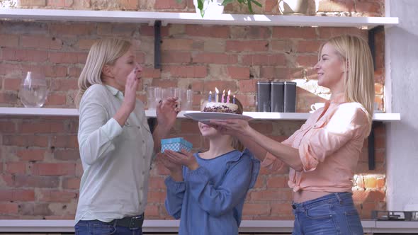 Surprise on Mother Birthday, Little and Adult Daughters with Gift and Holiday Cake with Candles