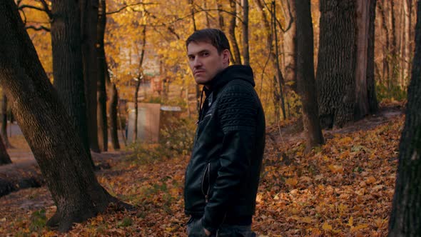 Portrait of a Young Handsome Man in Casual Clothes Against the Yellowed Trees in the Autumn Forest