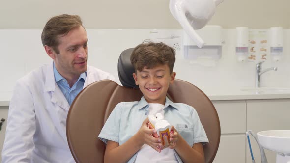 Happy Little Boy Showing Thumbs Up After Successful Dental Checkup with Dentist