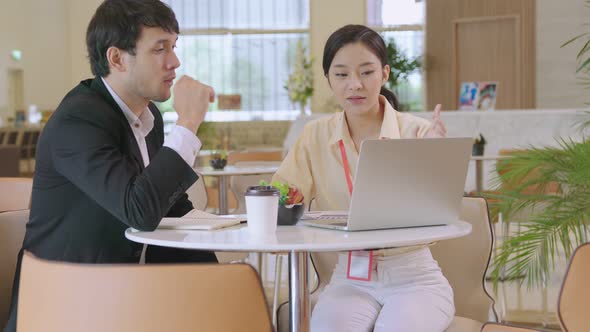 asian businessman and woman discuss together with laptop in modern office design