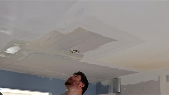 Man Plastering the Ceiling with Finishing Putty in Room with Putty Spatula
