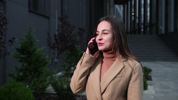 Woman Talking Phone Outside in American Style Business Center on the Background
