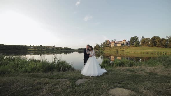 Caucasian Groom with Bride in the Park Near Lake. Wedding Couple. Newlyweds Kiss