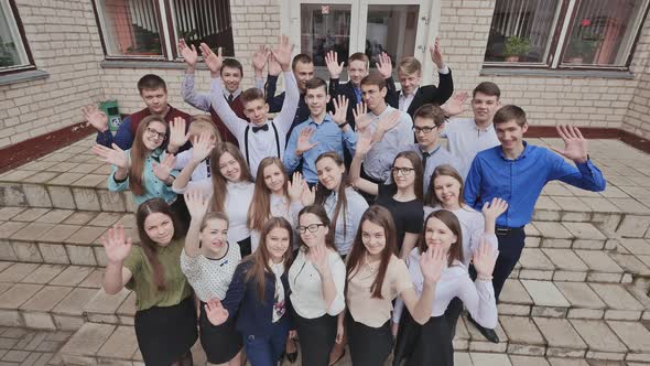 A Large Company of Happy Students Waving Their Hands on the Steps of Their School