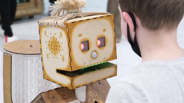 The Child Talks to a Wooden Robot the Latest Modern Robotic Technology