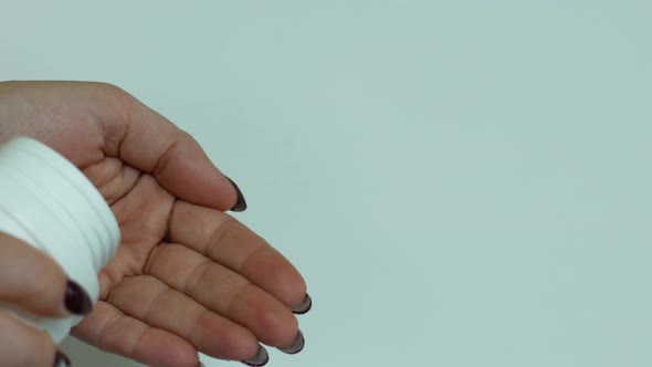 Close-up of a woman pouring a handful of pills into her hand. Vitamins for women's health theme.