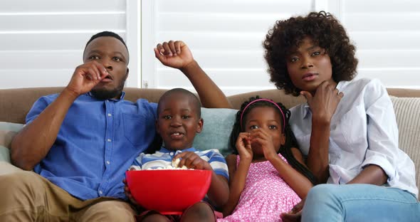 Family sitting on sofa and watching television