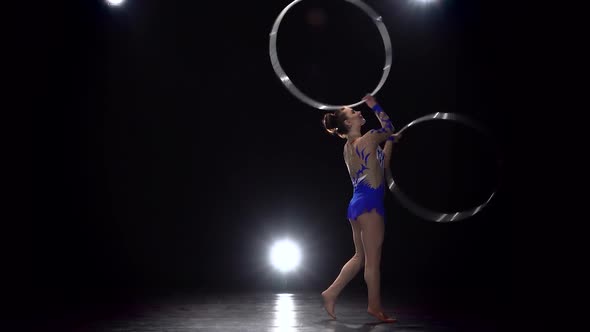 Gymnast in a Bright Outfit Twists a Hoop on Her Arm and Then on Her Leg