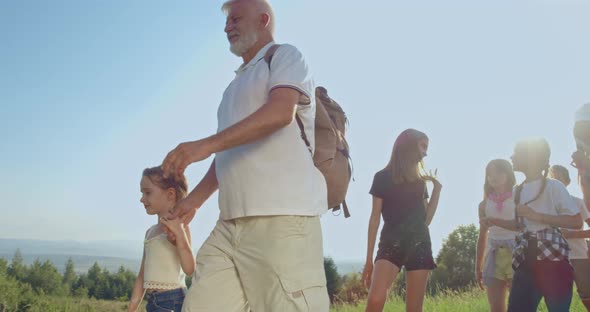 Children with Teacher Hiking in Mountains at Warm Summer Day