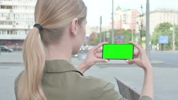 Woman Holding Horizontal Smartphone with Chrome Key Screen Outdoor