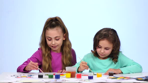 Children Paints a Picture, Dabs a Brush in a Glass with Water. Close Up. White Background