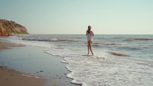 Happy Smiling Woman with Corgi Dog Running Along Seashore of Sea with Waves Feeling Wellness and