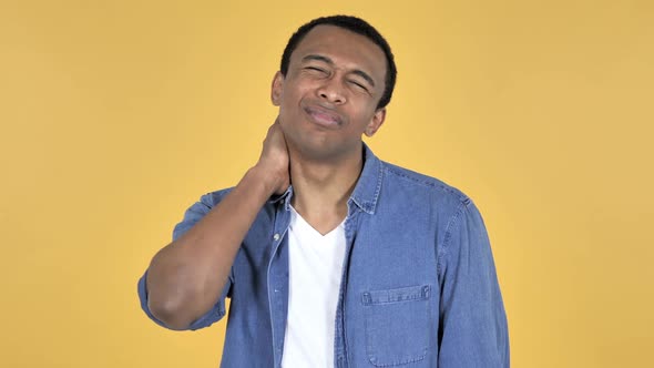 Young African Man with Neck Pain Yellow Background