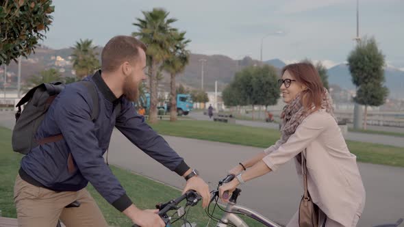 Two Happy Friends Are Saying By and Riding Bikes To Different Sides
