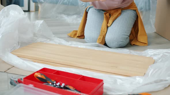 Young Woman Doing Woodwork Using Tools Making Shelf During Relocation