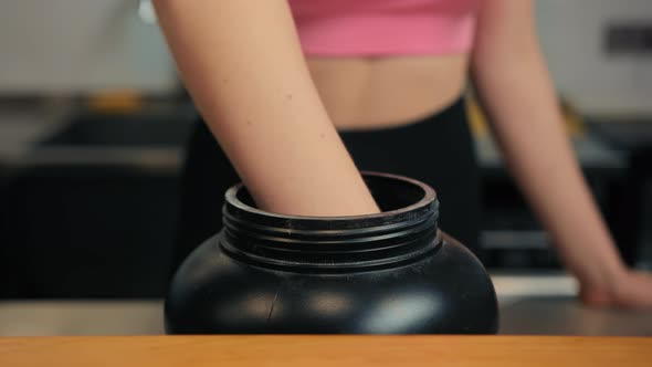 Close-up of a woman picking up protein from a jar