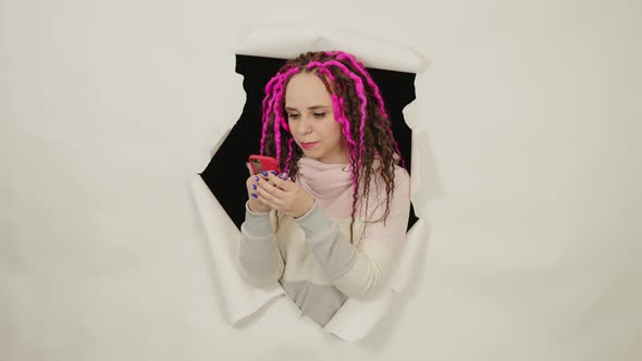 Young Woman with Curly Hair in Trendy Outfit Using Mobile Phone Standing on White Background