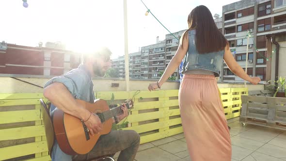 Musician plays guitar, woman stands next to him and starts to sing