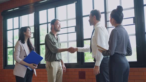 Group of business people making handshake for business deal while working and walking in office.