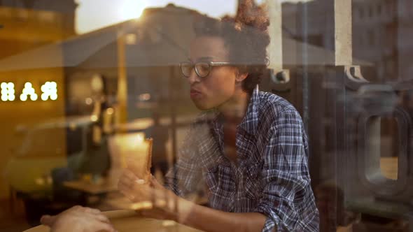 African Girl Eating Sandwich Speaking with Her Friend Behind Glass Slow Motion