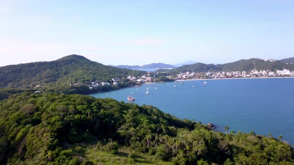 Aerial flying over a morro and revealing Bombinhas city on background in Brazil