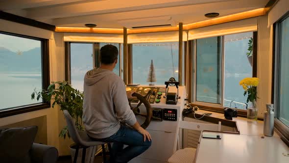 Man controls a steering wheel in a floating house on the sea in Montenegro in winter