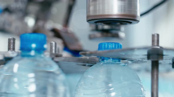 Water Factory Industrial Machine Puts Caps on Plastic PET Bottles with Water Close Up