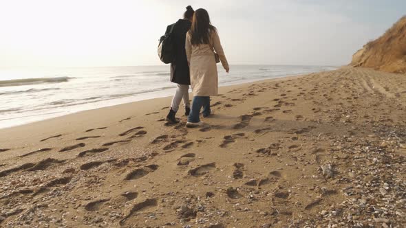 Happy Couple Walking on the Wild Beach on Cloudy Sunrise or Sunset