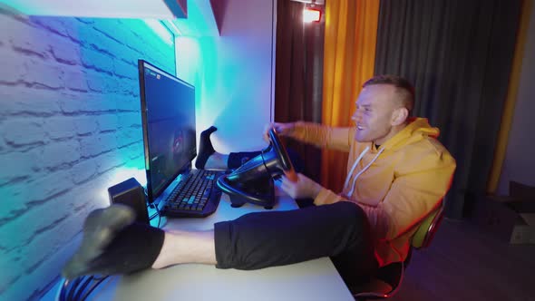 Driving game simulator. Side view of young man enjoying car racing video game