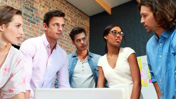 Businesspeople interacting while using laptop