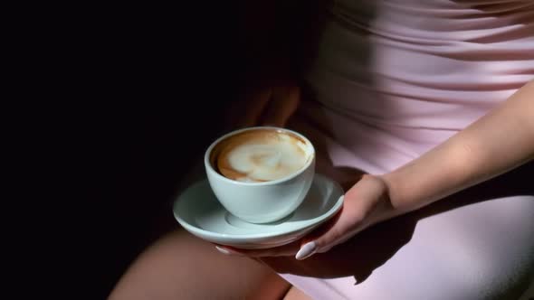 Closeup of Cup of Black Coffee and Saucer in Female Hands