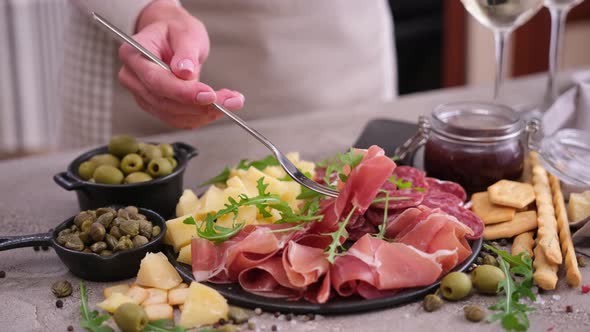 Meat and Cheese Plater at Domestic Kitchen  Woman Pricks Piece of Prosciutto Ham on a Fork