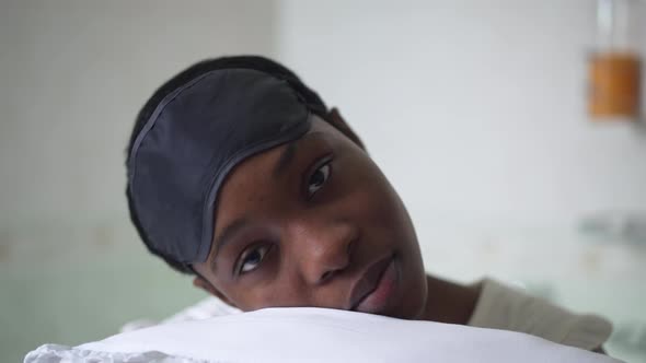 Tired Young African American Woman in Pajamas Putting Head on Pillow in Slow Motion Sitting in