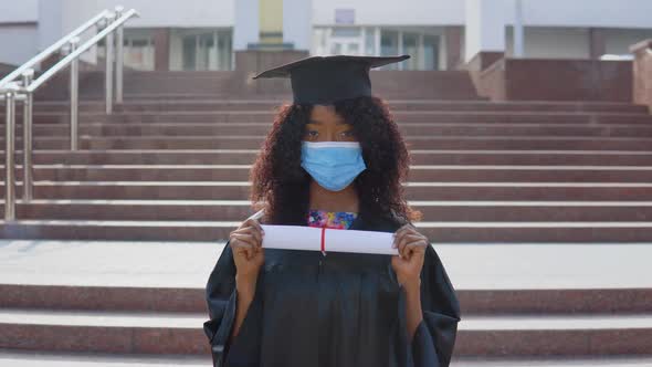 Young African American Female Graduate Standing in Front of the Camera with a Diploma in Her Hands