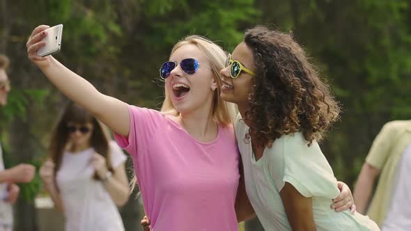 Two Beautiful Young Ladies Dancing, Laughing and Posing for Selfie on Smartphone