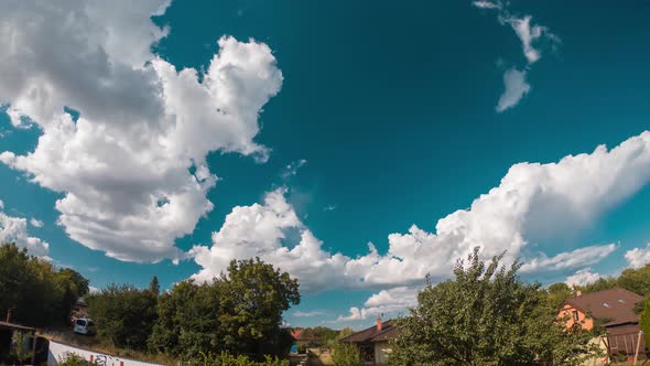 time lapse of clouds running over a turquoise sky above a suburb with houses