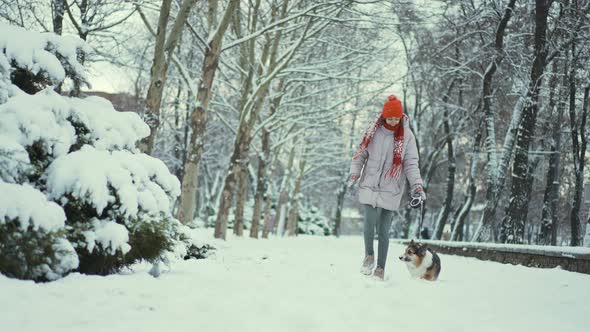 Slow Motion Beautiful Smiling Young Woman in Parka Knitted Red Beanie and Mittens Walks with Her